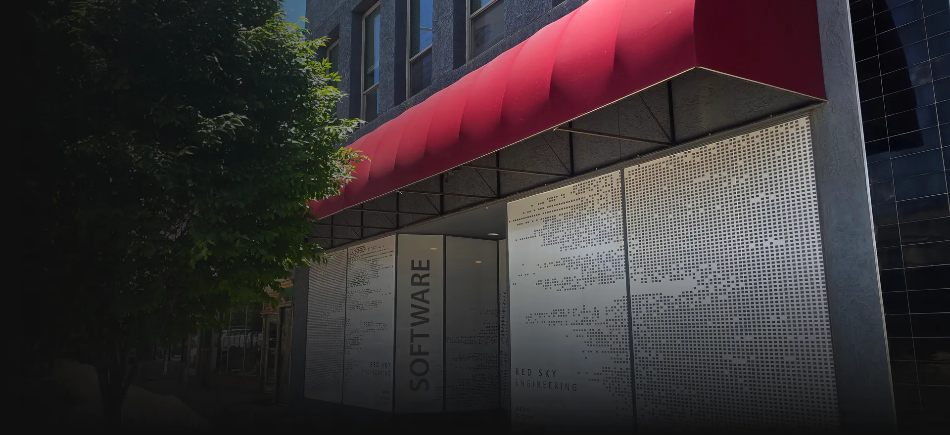 RedSky Engineering office storefront with a red awning and perforated SOFTWARE panels